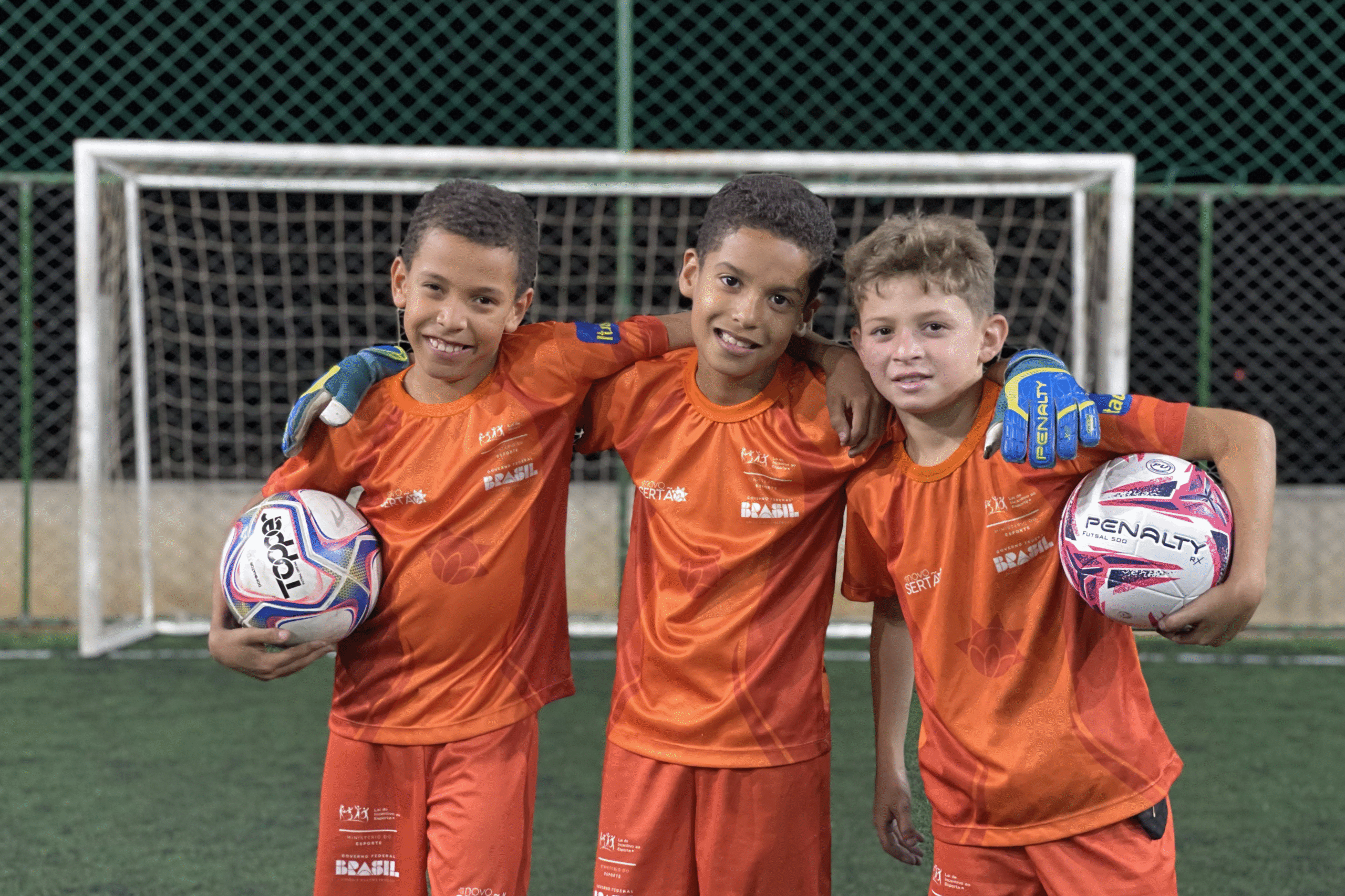 Alunos do projeto Futsertão segurando bolas e de uniformes, no treino 
